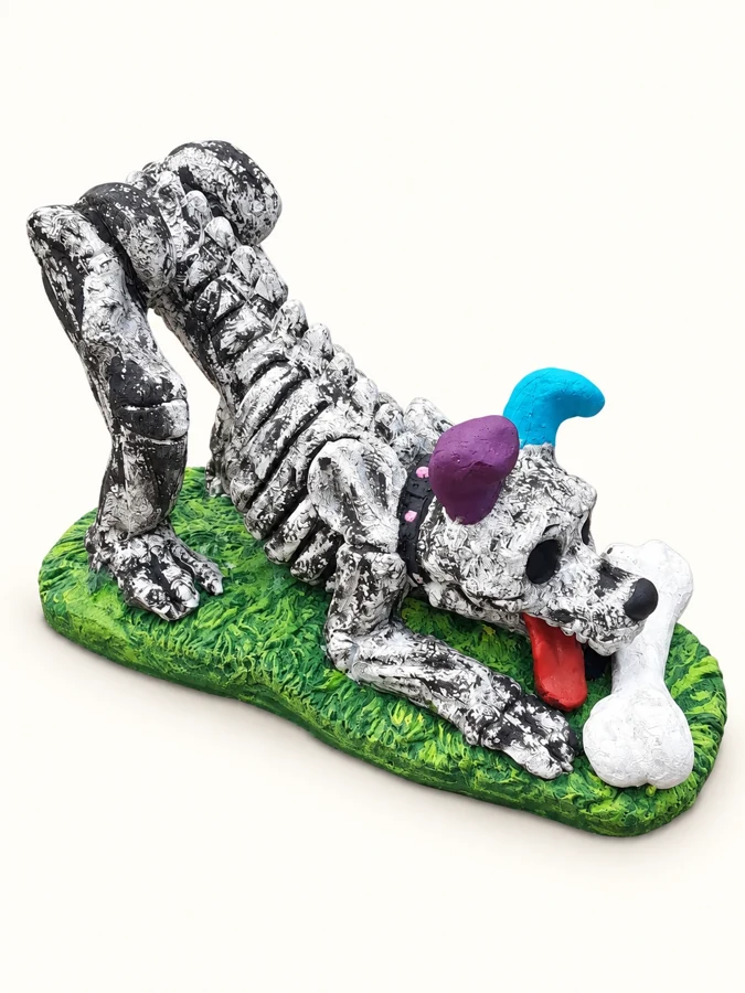 Decorative dog skeleton sculpture with purple and blue details and a white bone on a green base.